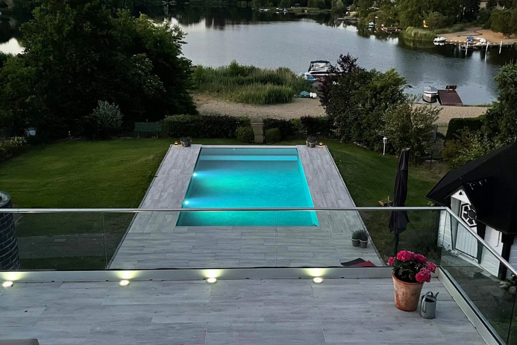 Beleuchteter Pool in der Abenddämmerung am Wasser